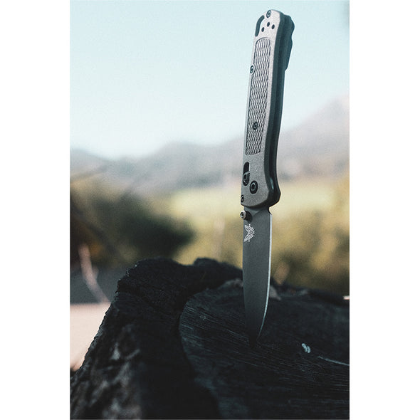 Benchmade 535GRY-1 Bugout Knife in Ranger Green. Blade in tree stump lifestyle image